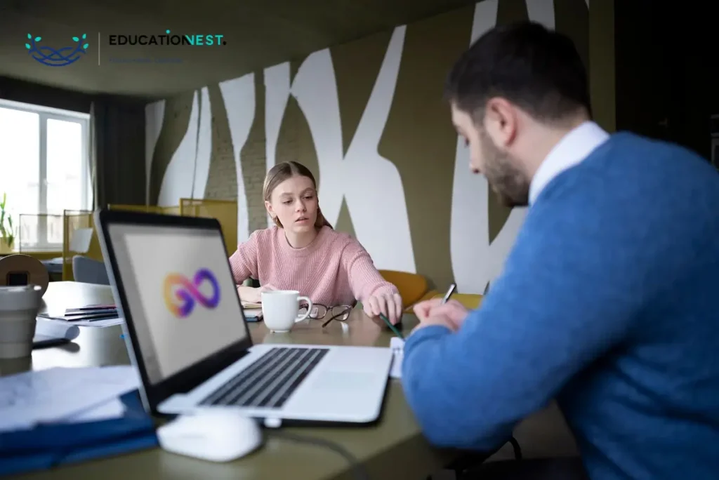 A man and woman collaborate at a table, focused on a laptop, discussing top DevOps practices for effective teamwork.