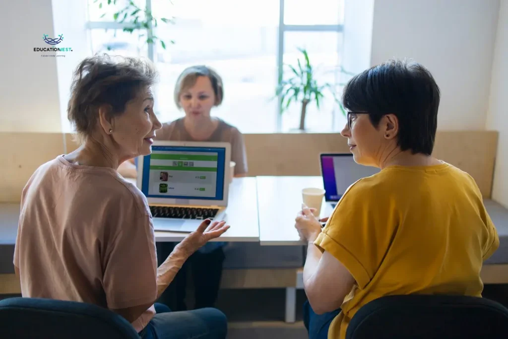 Three women engaged in a discussion at a table, each using a laptop, exemplifying networking skills for introverts.