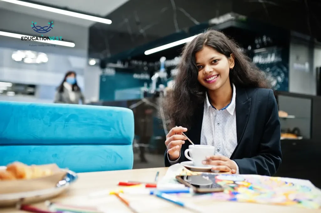 A woman dressed in a business suit sits at a table with a coffee, considering the key benefits of employee development.