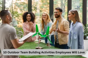 A diverse group of individuals stands around a table displaying a wind turbine, engaged in outdoor team-building activities.