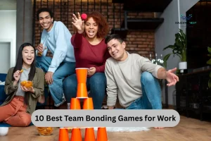 A group of colleagues engaged in a team bonding game, stacking and balancing a tower of orange cups together.