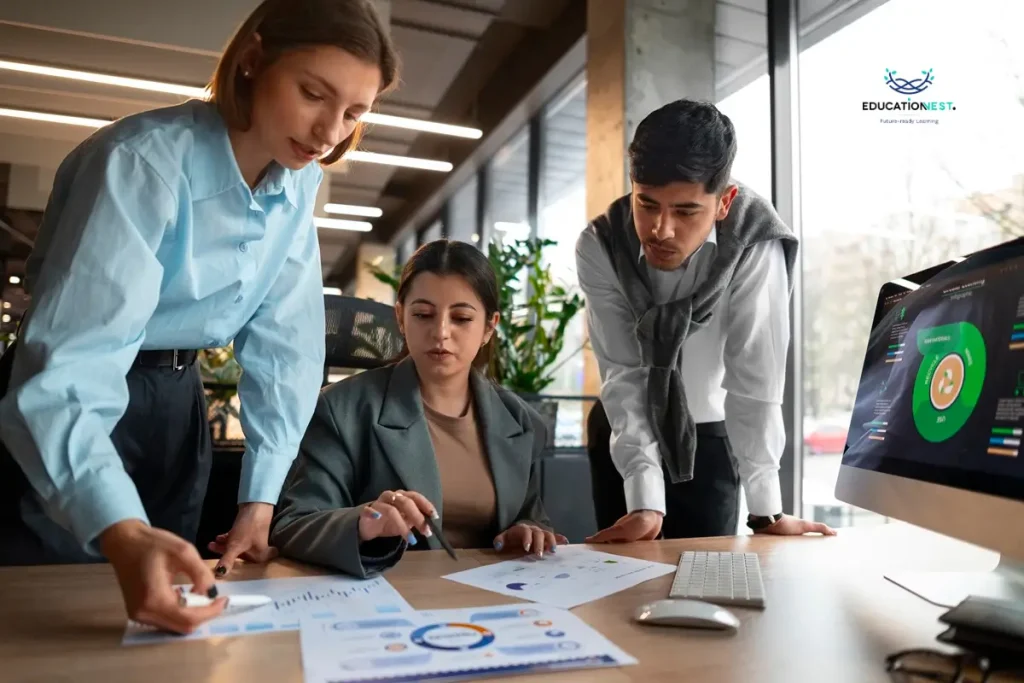 Three business professionals analyzing a computer screen displaying OKRs and KPIs in project management.