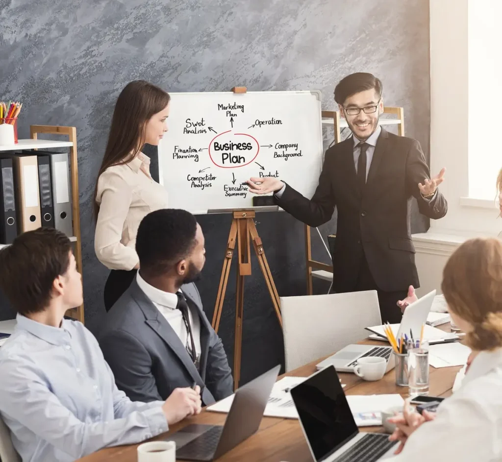 A group of employees engaged in soft skills training in a meeting room with a whiteboard.