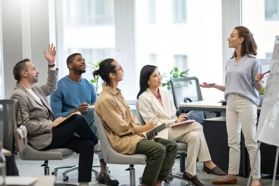 A woman presents to a group of people in an office setting, discussing the Employee Training Checklist.