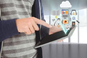 A man holding a tablet displaying icons related to EducationNest's Online Corporate Modules