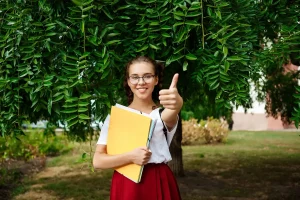 A girl holding a folder and giving a thumbs up, symbolizing enthusiasm for sustainability education.